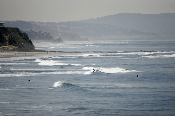 FILE - In this April, 2008, file photo, people swim and surf in the Pacific Ocean at Cardiff State Beach near Solana Beach, Calif., close to an area where a man was killed by a shark. (AP Photo/Lenny Ignelzi, File)
